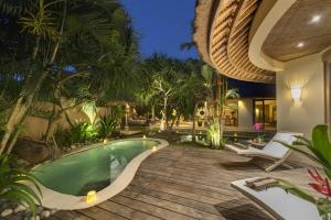 een buitenzwembad met stoelen en een huis bij Villa Tirta Naga Bali in Seminyak