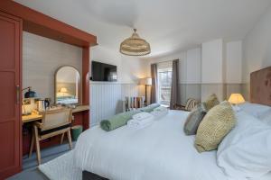 1 dormitorio con cama, escritorio y espejo en The Railway Hotel Worthing, en Worthing