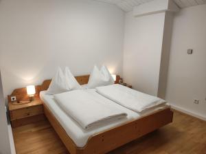 Schlafzimmer mit einem Bett mit weißer Bettwäsche und Kissen in der Unterkunft Amadee Appartements in Bad Kleinkirchheim
