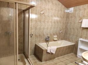 ein Bad mit einer Badewanne, einer Dusche und einem Waschbecken in der Unterkunft Amadee Appartements in Bad Kleinkirchheim