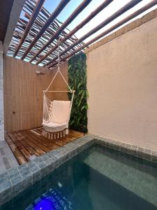a hammock sitting next to a swimming pool at Casa Natture Patacho in Pôrto de Pedras