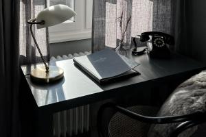 a desk with a lamp and a book on it at Såstaholm Hotell & Konferens in Täby