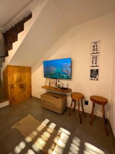 a room with two stools and a table and a tv at Casa Natture Patacho in Pôrto de Pedras