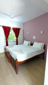 a bedroom with a large bed with red curtains at Santana Guest House in Agonda