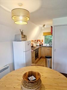 a kitchen with a wooden table with a white refrigerator at 19 the Coombe Charming, 2-Bedroom Family Chalet with Parking, Near Bude Beaches in Bude