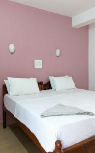 a bedroom with two beds and a pink wall at Santana Guest House in Agonda