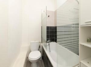 a white bathroom with a toilet and a bath tub at chez Elise in Toulon