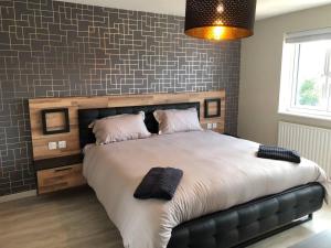 a bedroom with a large bed with a black leather couch at Luxury House in Camber Sand Beach is 2min Walk !! in Rye