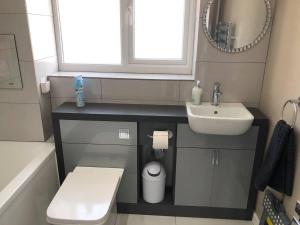 a bathroom with a sink and a toilet and a mirror at Luxury House in Camber Sand Beach is 2min Walk !! in Rye +26 photos