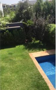 a backyard with a swimming pool and green grass at Maison entière Securisée à Casa Green Town in Casablanca