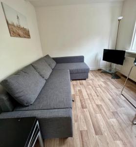 a living room with a couch and a television at Seaside Tiny House only 300 meters from the beach in Noordwijk