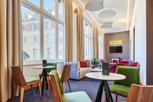 a waiting room with tables and chairs and windows at Le Grand Hôtel, The Originals Relais in Évaux-les-Bains