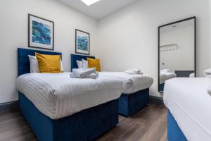 2 Betten mit blauen und gelben Kissen in einem Zimmer in der Unterkunft Temple Court by UStay Aparthotels in Liverpool