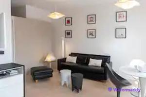 uma sala de estar com um sofá preto e cadeiras em La Suite - T2 Prestige - Hypercentre em Albi