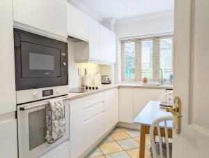 a kitchen with white cabinets and a tv at Wisteria Way, Tangmere in Tangmere