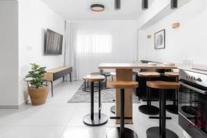 una cocina blanca con mesa y taburetes en דירה משפחתית מרווחת 50 מטר מהים - By Edom, en Eilat