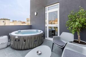 a large tub sitting on a balcony with a table and chairs at Oasis Penthouse Luxury Suite by Solea in Sliema