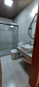 a bathroom with a sink and a toilet and a mirror at Villaggio di Itália Chalés in Santa Teresa