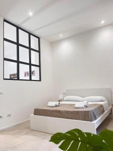 a white bedroom with a large bed and a window at Valguarnera Studio Apartments in Palermo