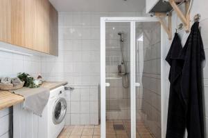 a bathroom with a shower and a washing machine at Room in a spacious villa in Stocksund