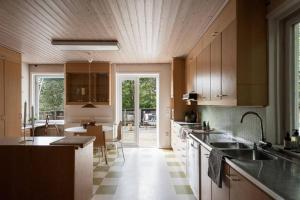 Room in a spacious villa في Stocksund: مطبخ مع دواليب خشبية وغرفة طعام