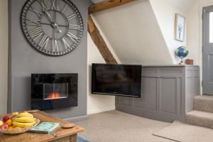 ein Wohnzimmer mit einer großen Uhr und einem Kamin in der Unterkunft The Loft: Unique, romantic, grade II listed, dog friendly in Stow on the Wold