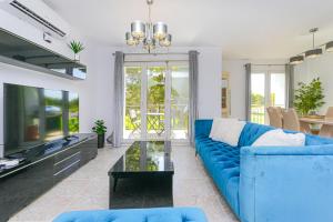 uma sala de estar com um sofá azul e uma televisão em Presidential suite Villamartin Plaza First line Golf Quiet and confortable em Alicante