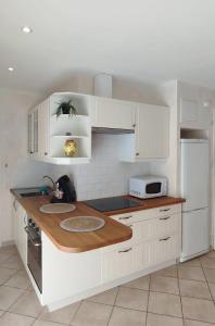 uma cozinha com armários brancos e um frigorífico branco em T2 CALME + cadre verdoyant em Besse-sur-Issole