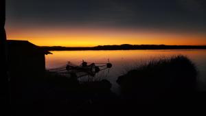 a boat sitting on the water at sunset at Uros Utasa Lodge in Puno