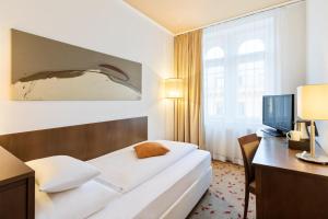 una camera d'albergo con letto, scrivania e TV di Hotel Rathauspark Wien, a member of Radisson Individuals a Vienna