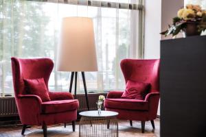 فندق تريند النمسا أوروبا سالزبورغ في سالزبورغ: كرسيين حمر ومصباح في غرفة المعيشة