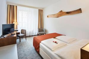 a hotel room with a bed and a flat screen tv at Austria Trend Hotel Europa Wien in Vienna +40 photos