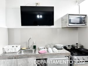 cocina con fregadero y TV en la pared en Departamento Miraflores, en Lima