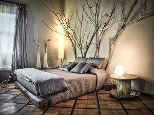 a bedroom with a bed with a tree on the wall at Bed+Art Milano Centrale in Milan