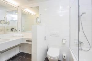 a white bathroom with a toilet and a shower at Hotel Schillerpark Linz, a member of Radisson Individuals in Linz