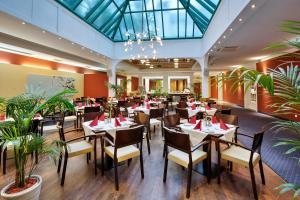 a restaurant with tables and chairs and plants at Austria Trend Hotel Ananas Wien in Vienna