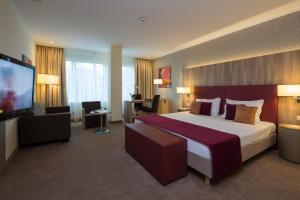 a hotel room with a large bed and a flat screen tv at Hotel Schillerpark Linz, a member of Radisson Individuals in Linz