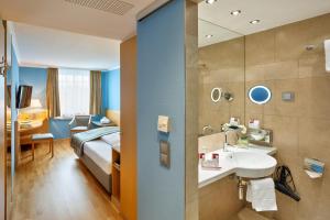 a bathroom with a bed and a sink in a room at Austria Trend Hotel Ananas Wien in Vienna +81 photos