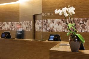a lobby with a reception desk with a vase of flowers at Austria Trend Hotel Savoyen Vienna - 4 stars superior in Vienna