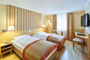 Habitación de hotel con 2 camas y escritorio en Austria Trend Hotel Ananas Wien, en Viena