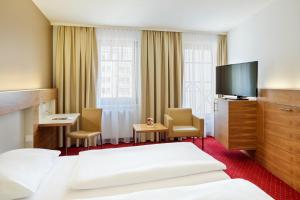 a hotel room with a bed and a flat screen tv at Austria Trend Hotel Anatol Wien in Vienna