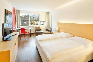 インスブルックにあるオーストリア トレンド ホテル コングレス インスブルックのベッド、デスク、キッチンが備わるホテルルームです。