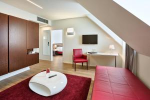 a living room with a red chair and a table at Austria Trend Hotel beim Theresianum Wien in Vienna