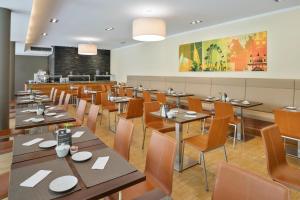 uma sala de jantar com mesas e cadeiras de madeira em Austria Trend Hotel beim Theresianum Wien em Viena