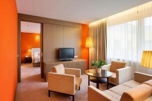 a hotel room with a couch and chairs and a television at Austria Trend Hotel Savoyen Vienna - 4 stars superior in Vienna