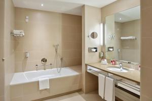 a bathroom with a tub and a sink and a mirror at Austria Trend Hotel Savoyen Vienna - 4 stars superior in Vienna