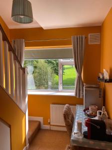 um quarto amarelo com uma janela e uma mesa em ByTheSea em Malahide