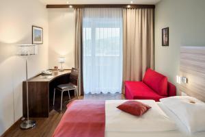 ein Hotelzimmer mit einem Bett, einem Schreibtisch und einem roten Stuhl in der Unterkunft Austria Trend Hotel Salzburg Messe in Salzburg