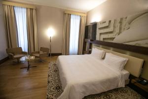 a hotel room with a white bed and a chair at Risorgimento Resort in Lecce