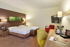 ウィーンにあるオーストリア トレンド ホテル ドッピオ ウィーンのベッド、デスク、椅子が備わるホテルルームです。